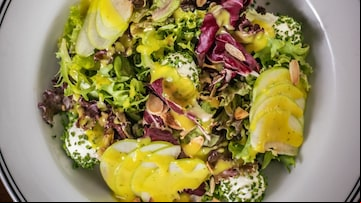 Salada com diferentes tipos de alface, queijo bolinha, maçã verde laminada, molho mostarda e mel e cebolete picado e salpicado por cima. Tudo isso, em um prato fundo de louça branco. Foto: Chez Amis Bristô/Divulgação