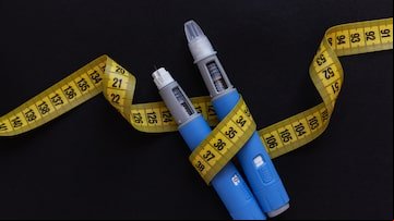 Two drugs injection pens ozempic for weight loss with a measuring yellow tape on a black background. Medicine for diabetics and weight loss. Foto: alones/Adobe Stock
